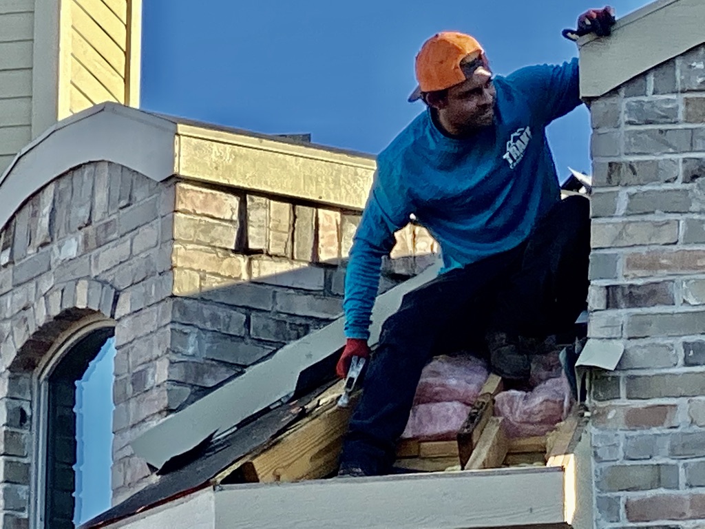 Trake Construction roofer repairing chimney flashing on a Rockwall home