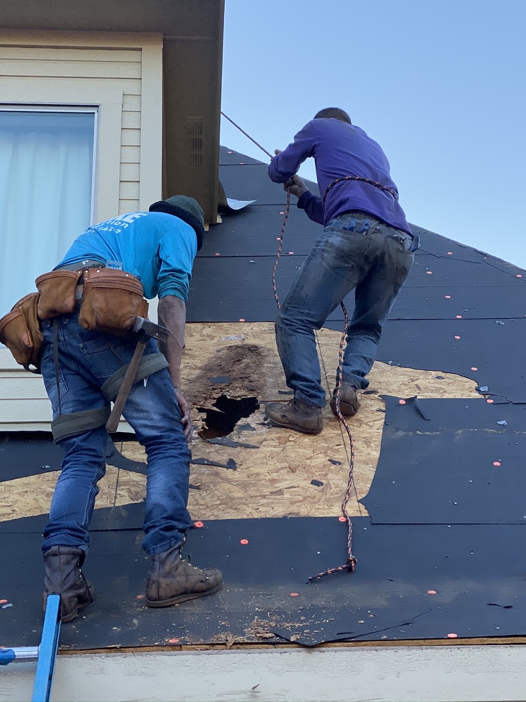 Two Trake Construction crew members replacing damaged roof decking