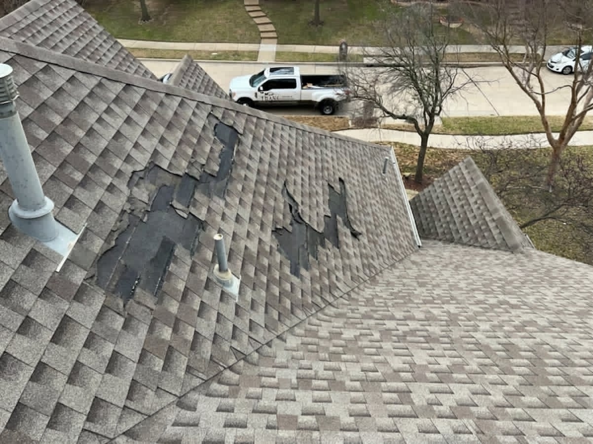 Storm-damaged shingles before and full shingle replacement after by Trake Construction — before